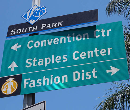 Sign post in downtown LA with directions to Los Angeles Conventi Green street sign with arrows pointing to different destinations.